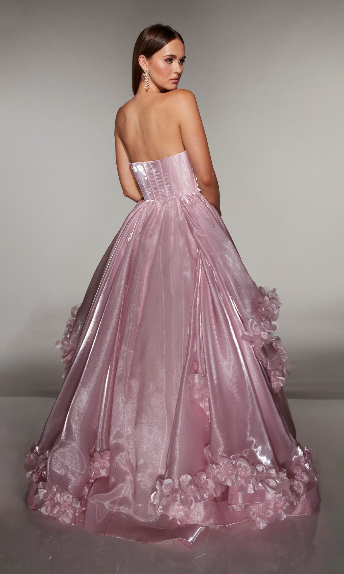 A woman stands facing away, looking over her shoulder in the Alyce 62014 Long Prom Dress—a strapless ballgown made from liquid organza with 3D floral appliques.